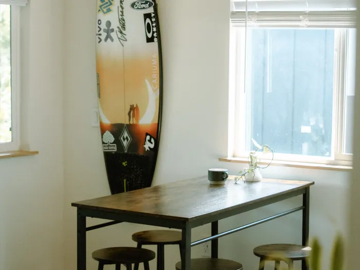 Dining table and surfboard inside the Haleiwa surf camp accommodation
